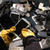 一位开云体育最新官网入口网址戴着防护手套的Stena回收专家正在整理一个装满废旧手机的容器